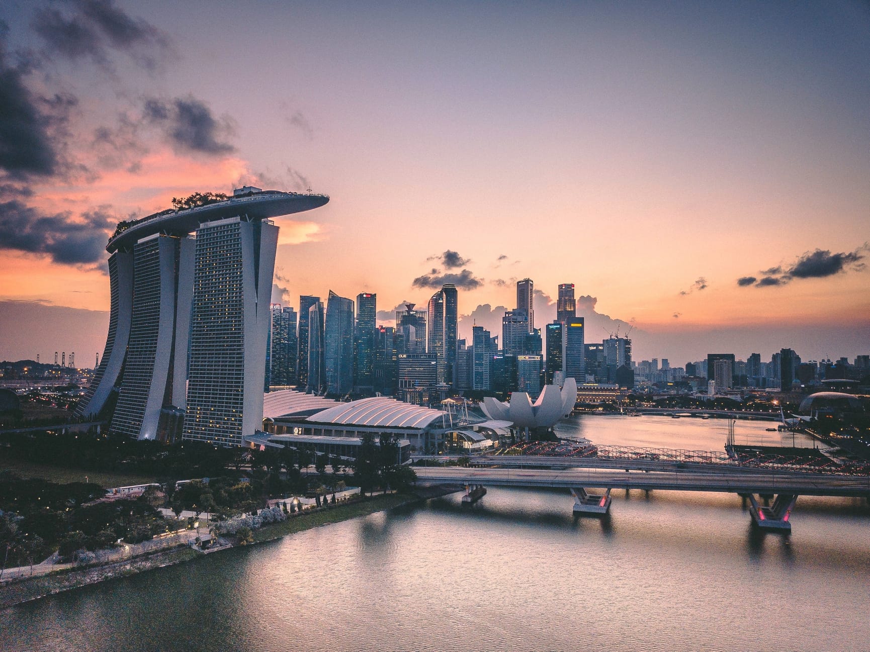 City skyline of Singapore at sunset with Marina Bay Sands on left side.