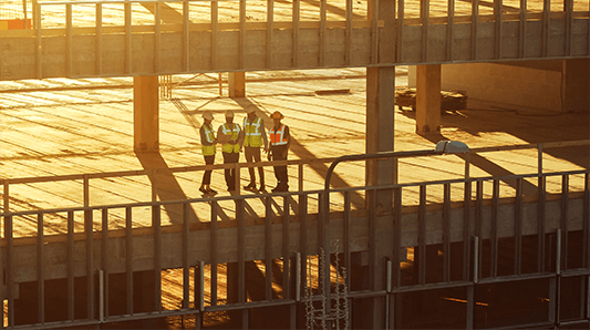 Construction site at sunset with four people in hi-vis.