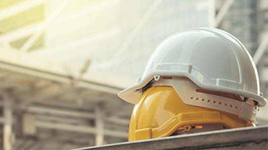 Two hard helmets on a table in front of glass buildings