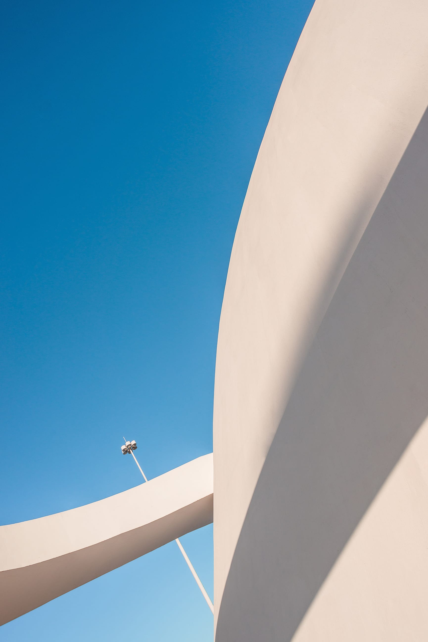 Architectural detail of a cream curved building against a blue sky background
