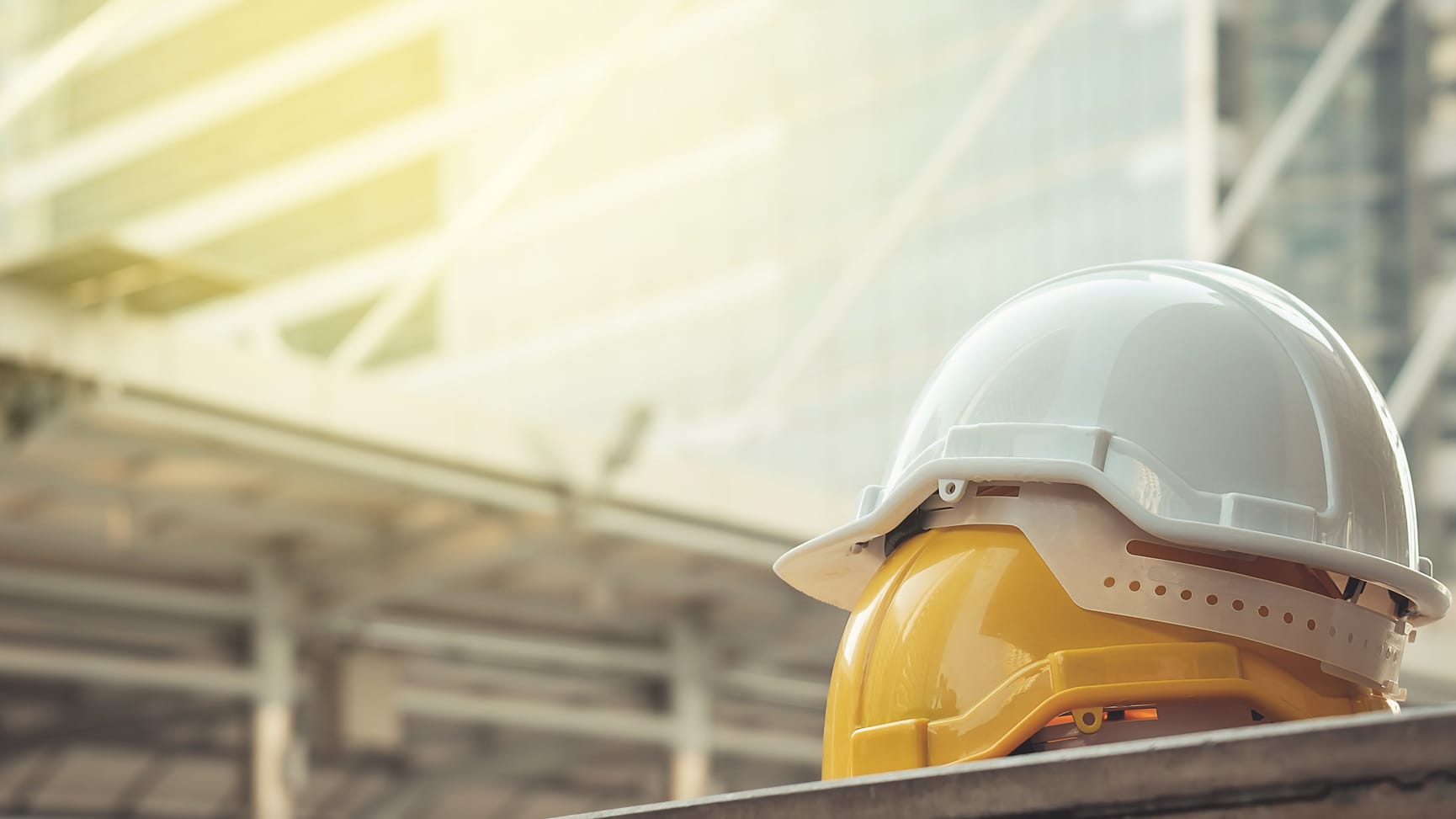 Two hard helmets on a table in front of glass buildings